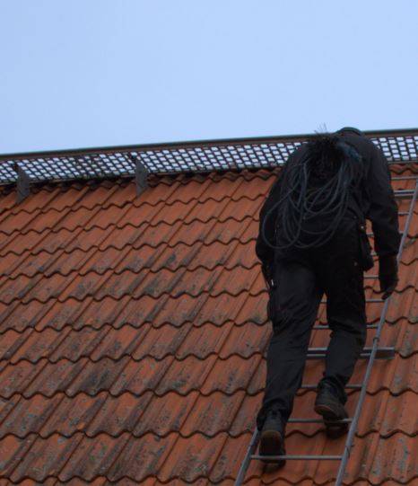 Syntolkning av bild: Sotare som klättrar på hustak