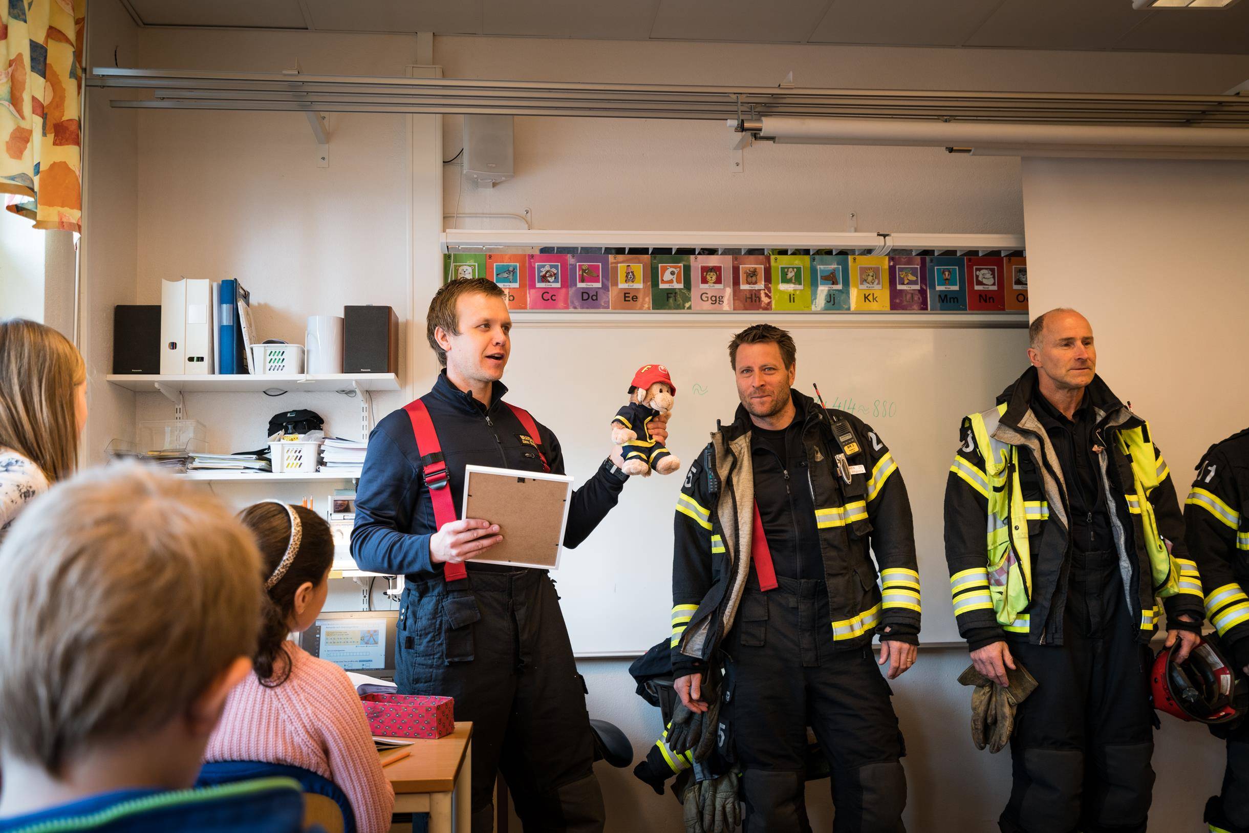 Syntolkning av bild: Brandmän håller utbildning för skolelever