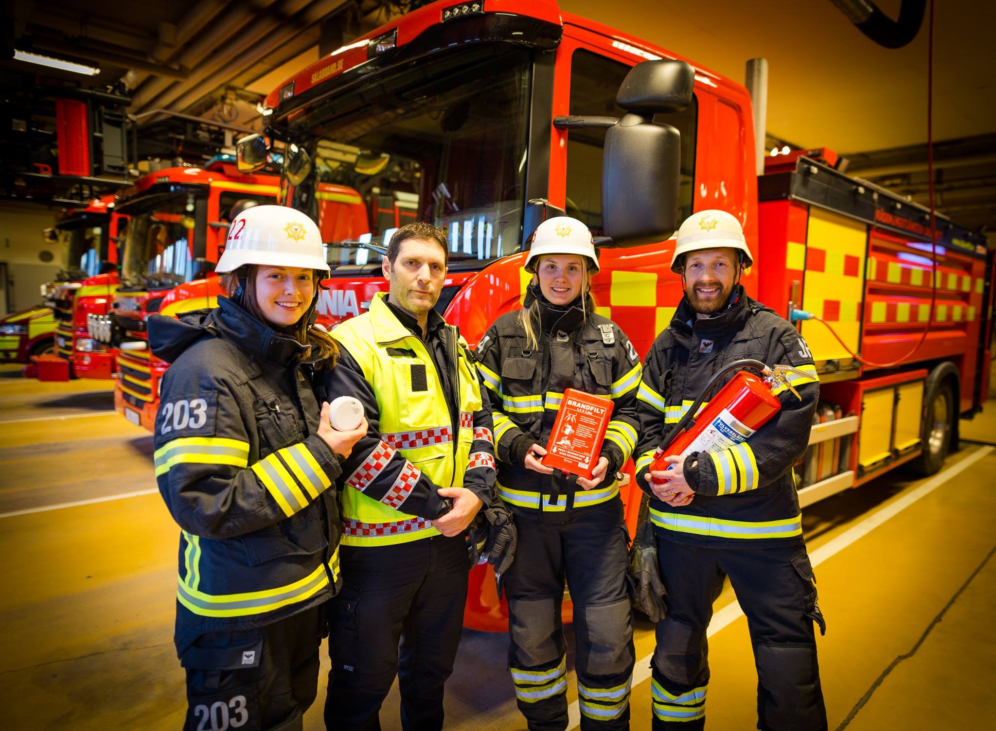 Syntolkning av bild: Fyra brandmän som visar brandskyddsutrustning
