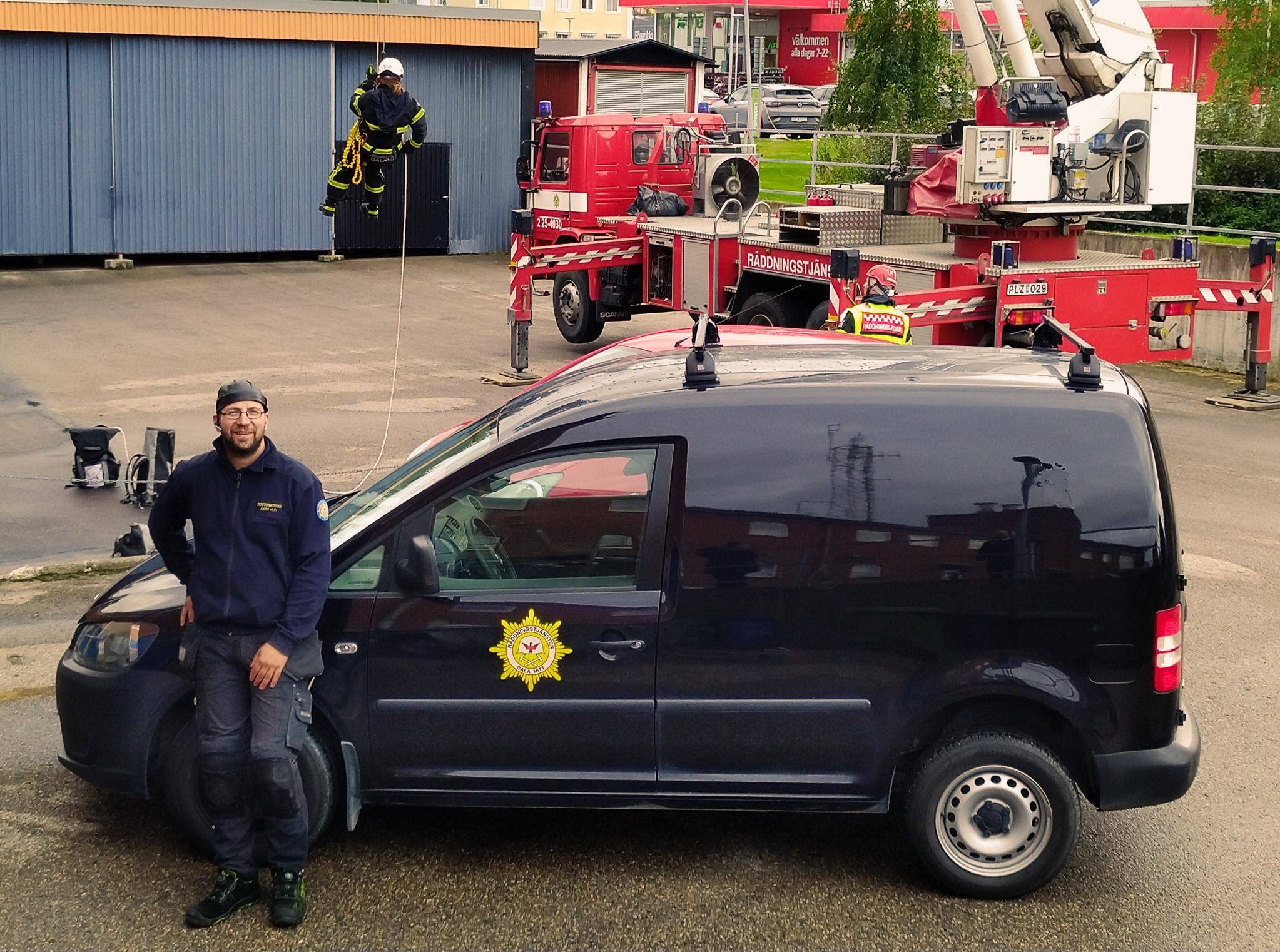Syntolkning av bild: Brandskyddskontrollant stående utomhus vid arbetsbil.