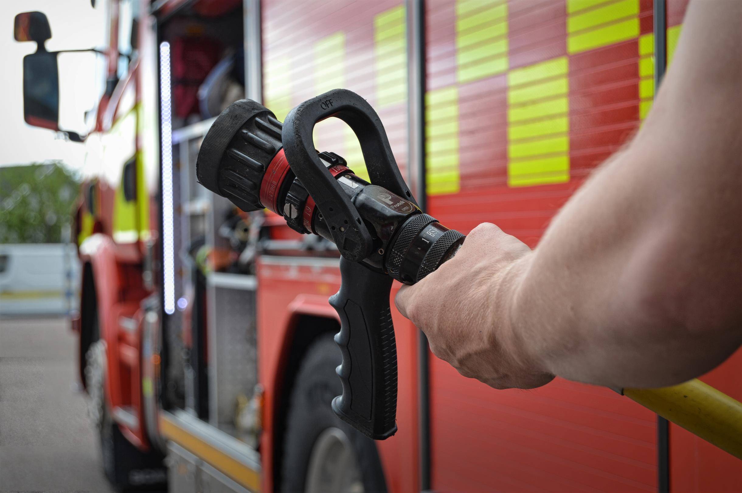 Syntolkning av bild: Brandman håller i sprutmunstycke till brandslang