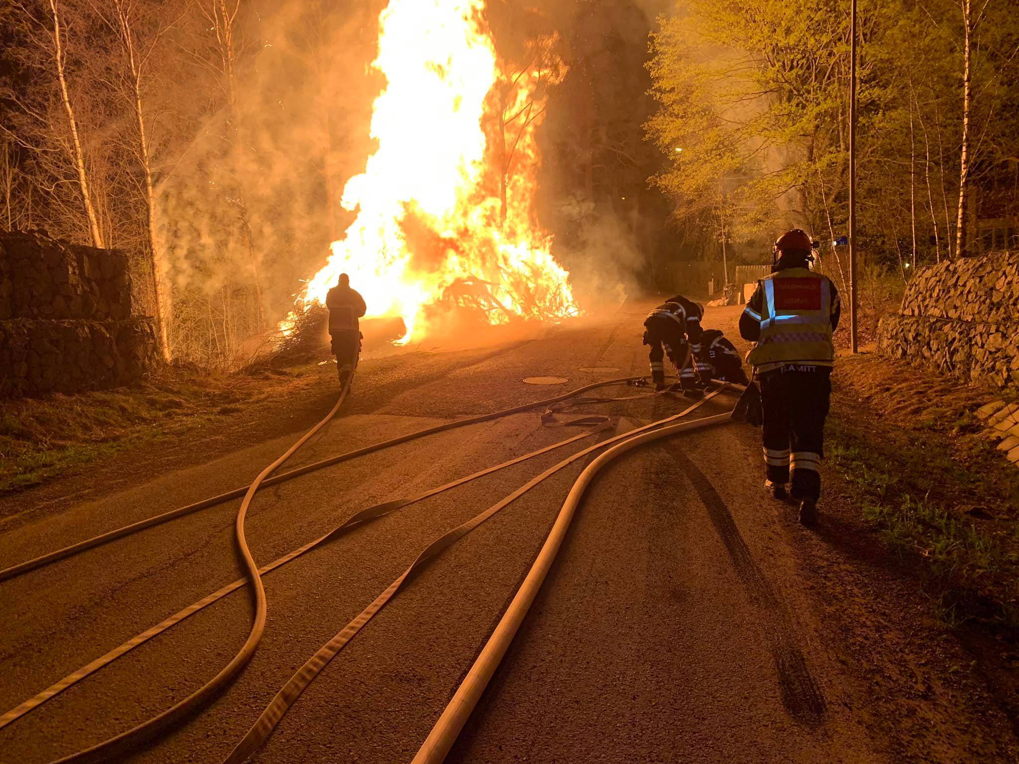 Syntolkning av bild: Brandmän släcker en brinnande rishög